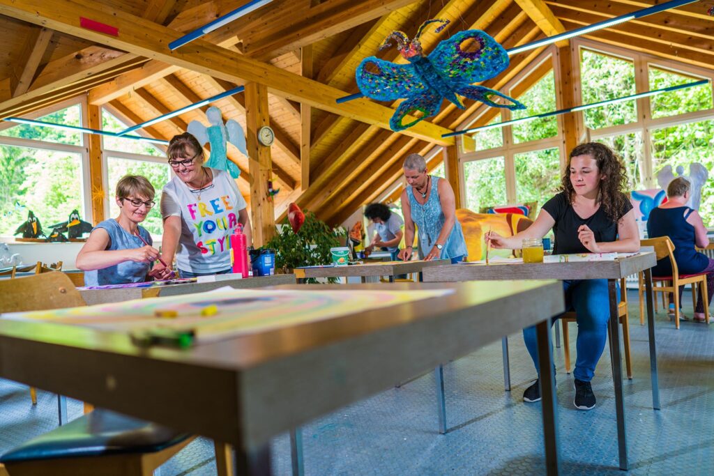 Patientinnen und Patienten bei kreativer künstlerischer Tätigkeit in einem hellen Atelierraum.
