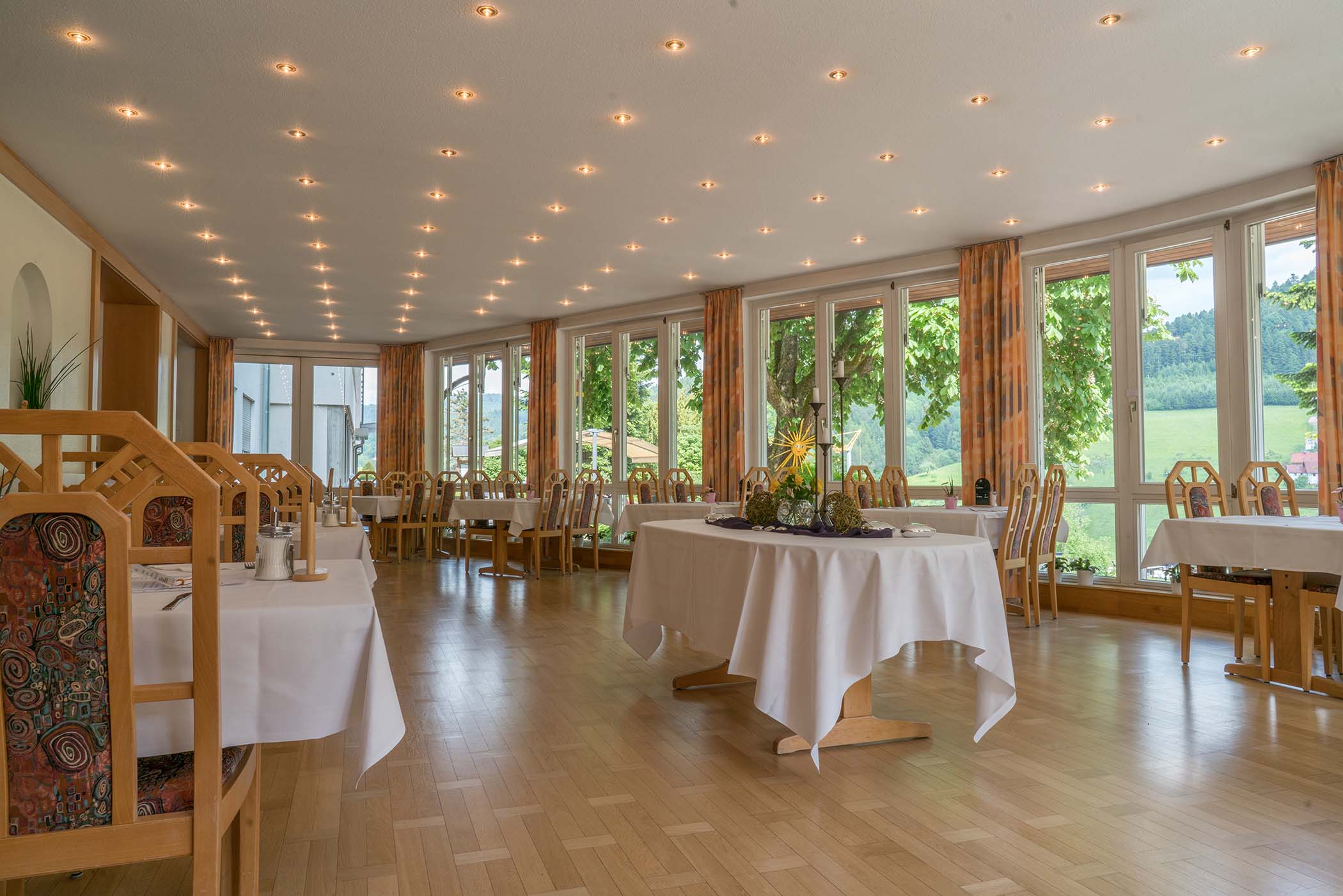 Heller Speisesaal der Winkelwaldklinik Nordrach mit gedeckten Tischen und großen Fenstern mit Blick in die Natur.